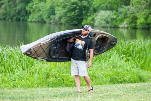 Adam carrying a kayak while wearing the Alliance Retro T-shirt.