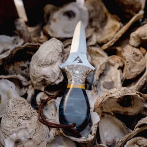 Oyster knife laying on a bed of oyster shells.