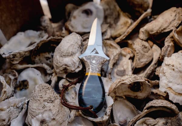 Oyster knife laying on a bed of oyster shells.