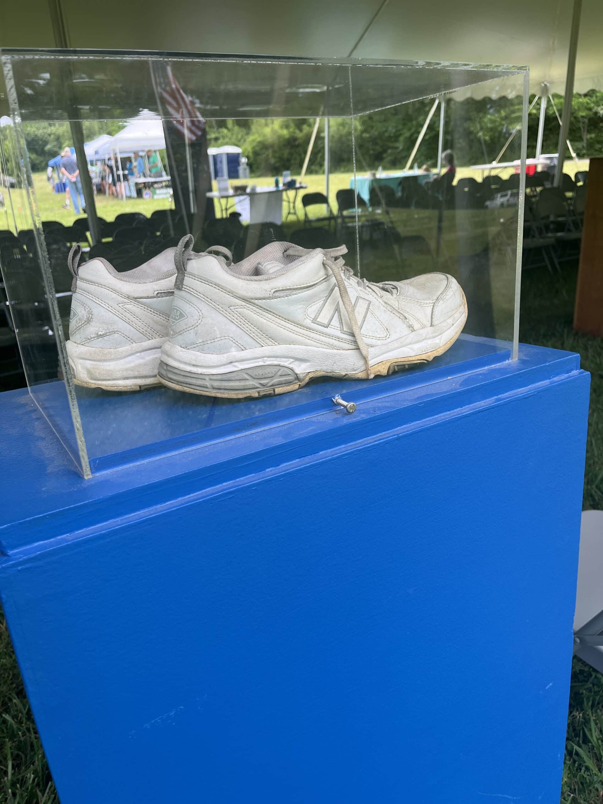 A pair of white shoes in a clear display case