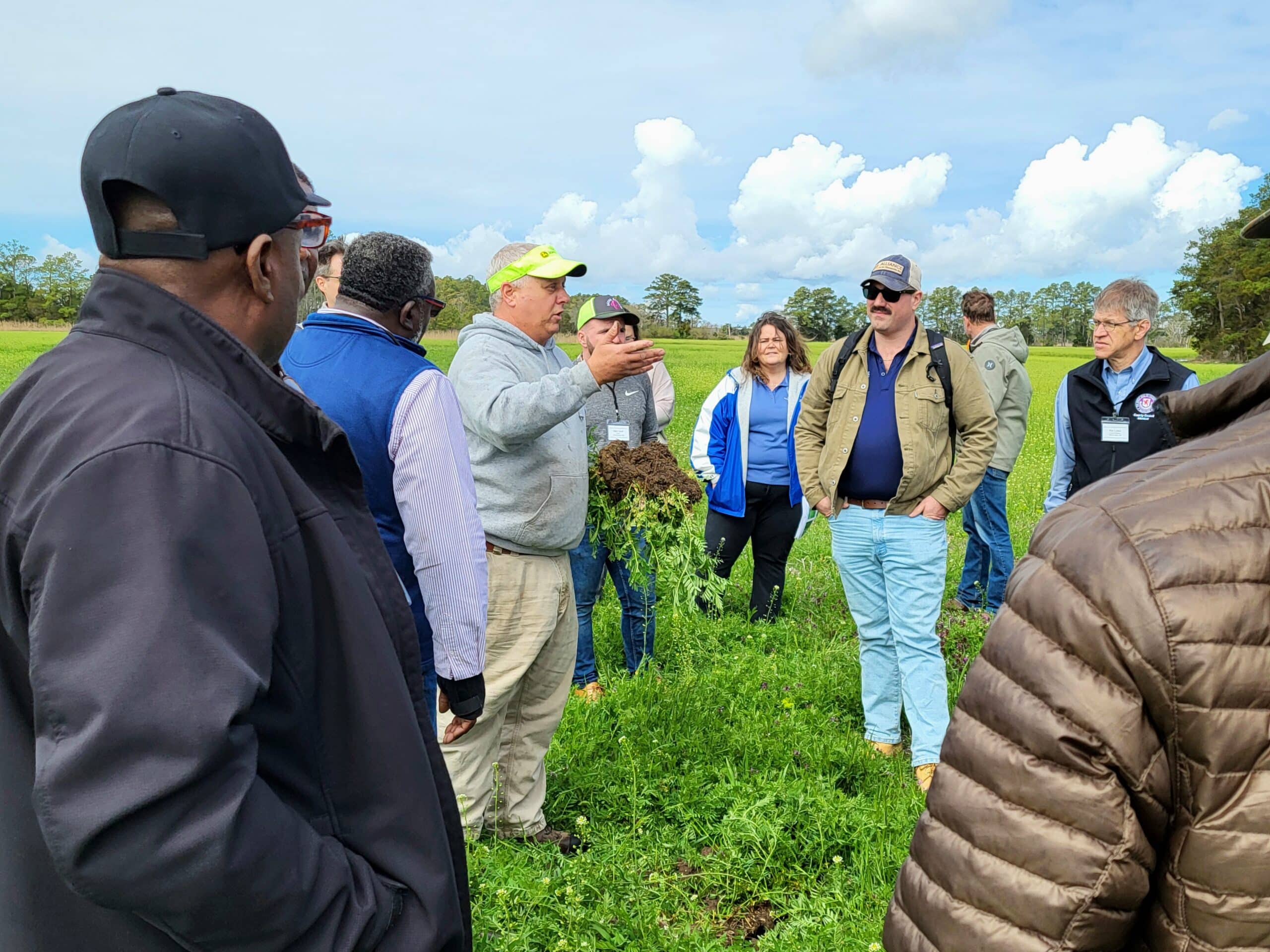 A group of people listening to a person speak while holding plants and soil