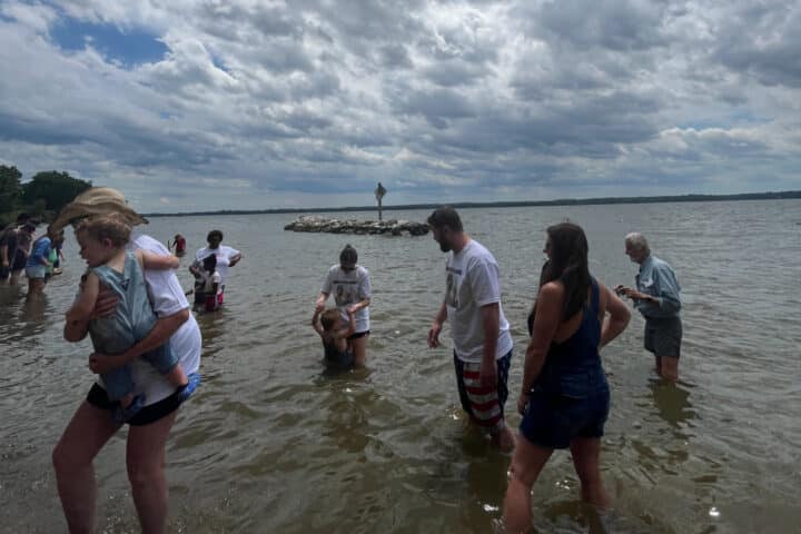 A group of people wade into the the side of a river