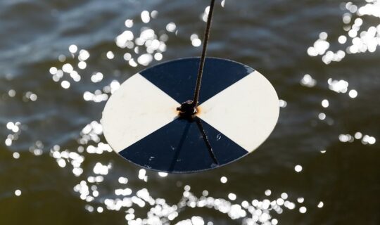 A close up of a black and white disk over water