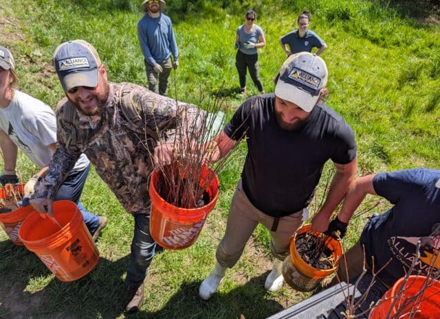 An overhead view of a line of people carrying buckets and smiling