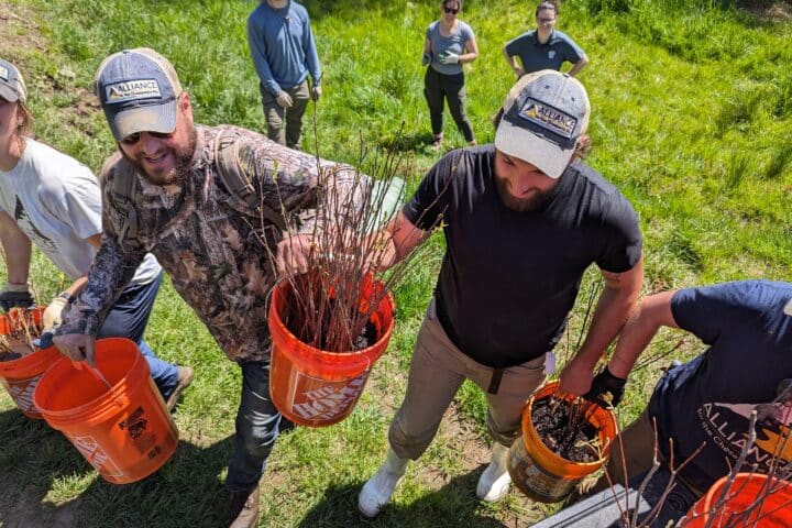 An overhead view of a line of people carrying buckets and smiling