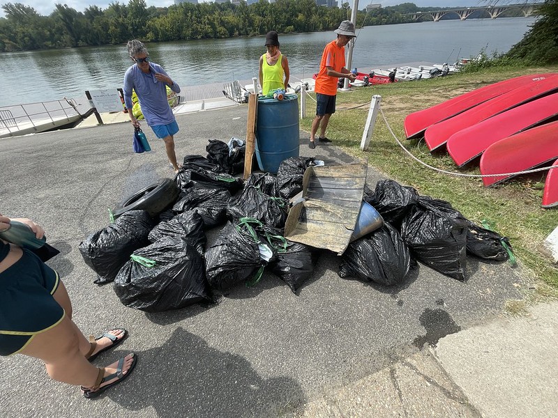 Volunteers add their collected trash to a pile of black bags filled with litter collected on the Anacostia River 