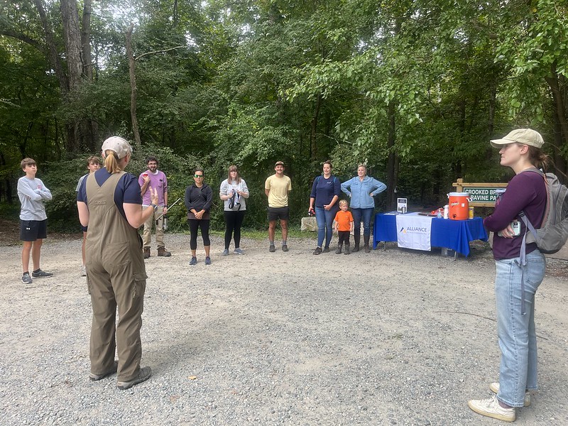 A group of volunteers gather around the Project Clean Stream site captain.