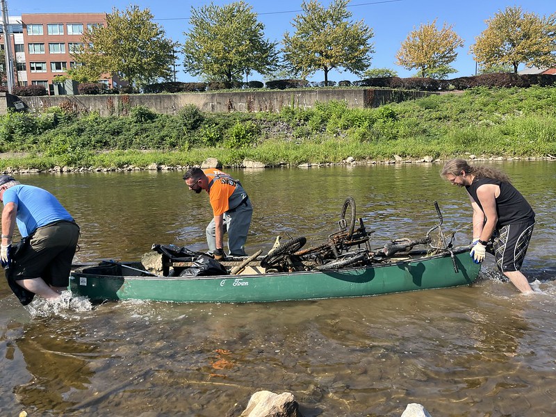 Three volunteers guide a canoe holding their found trash through the Codorus Creek.