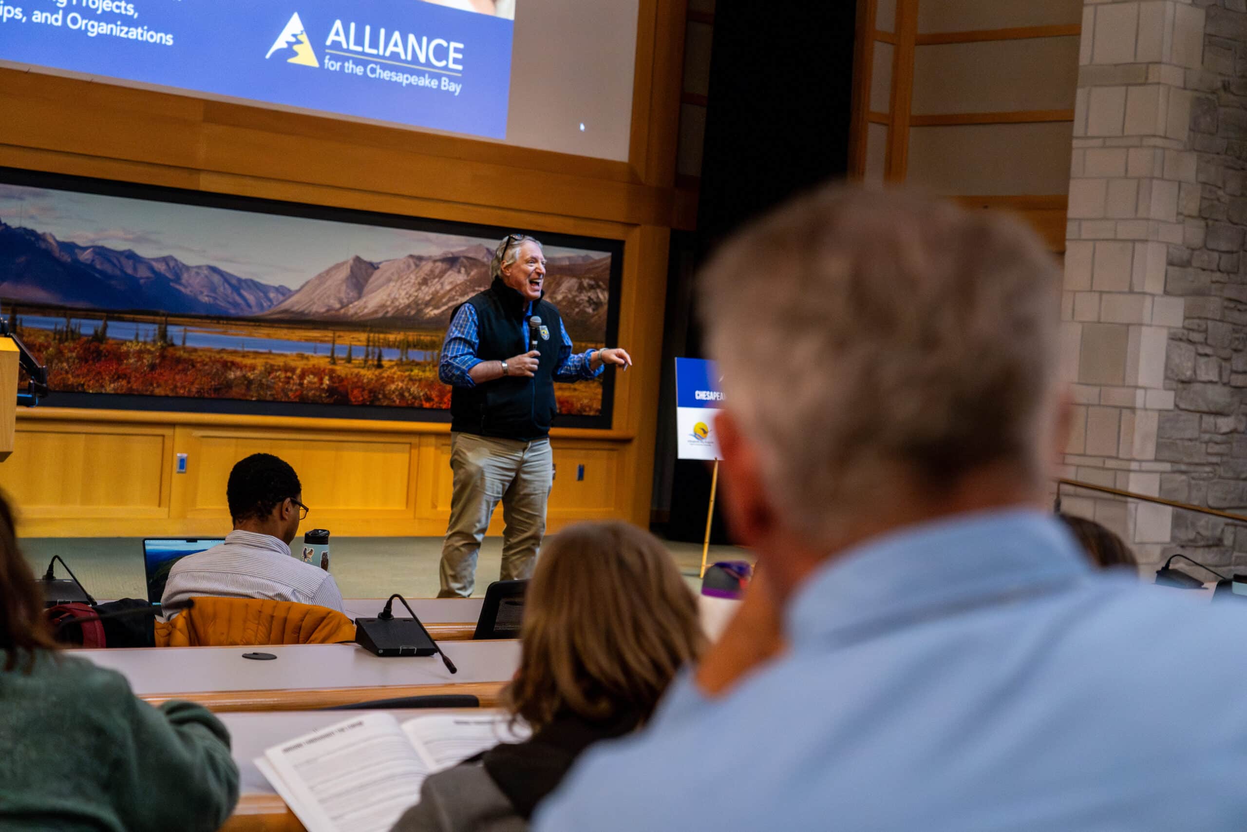 A person on stage speaking to an auditorium of people