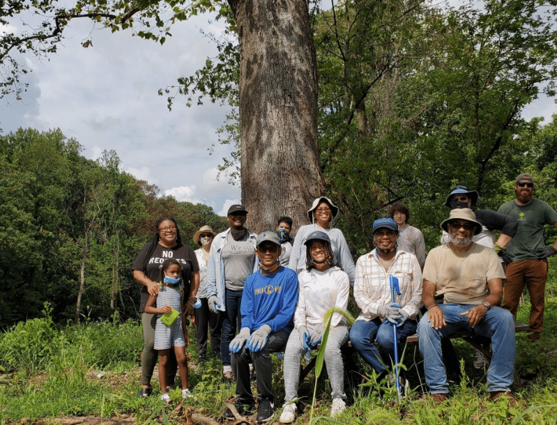 a group of people posing for a picture in front of a large tree