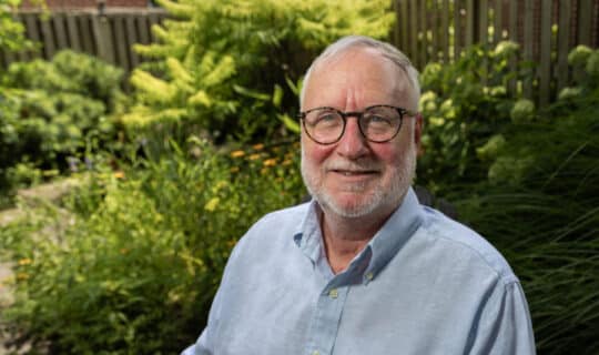 A person sitting in a yard full of plants