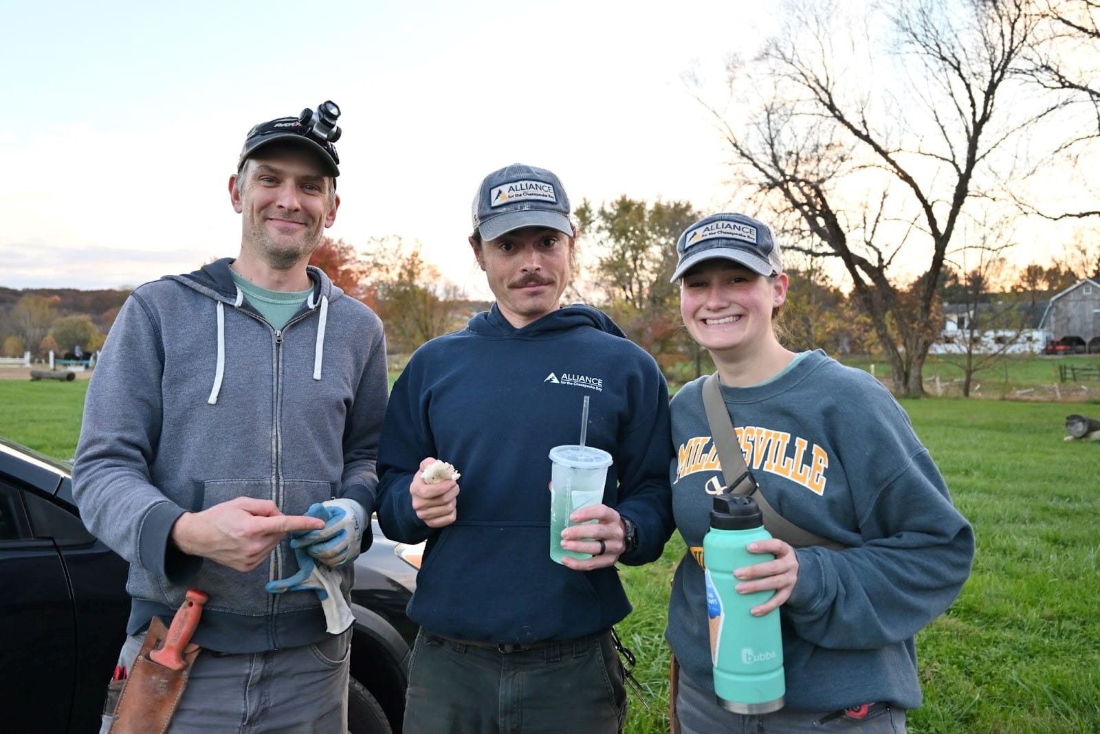 Three people posing for a picture in a field