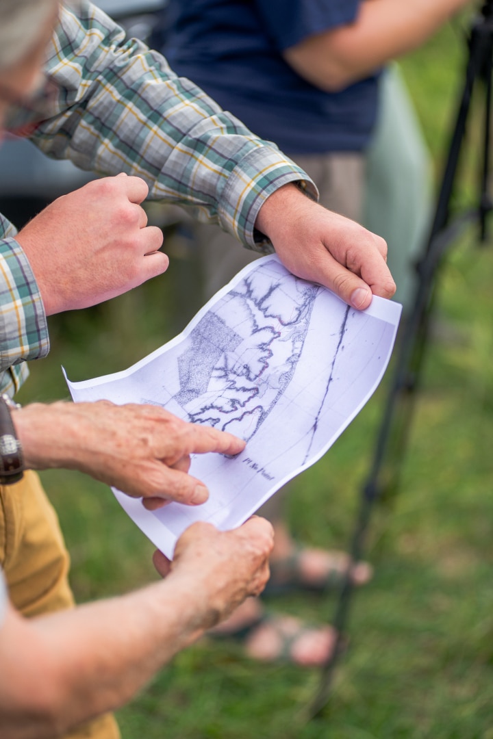 People point at a historic map of the area